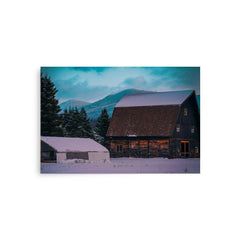 Snow-covered barn and trees with Adirondack Mountain in the background at twilight.