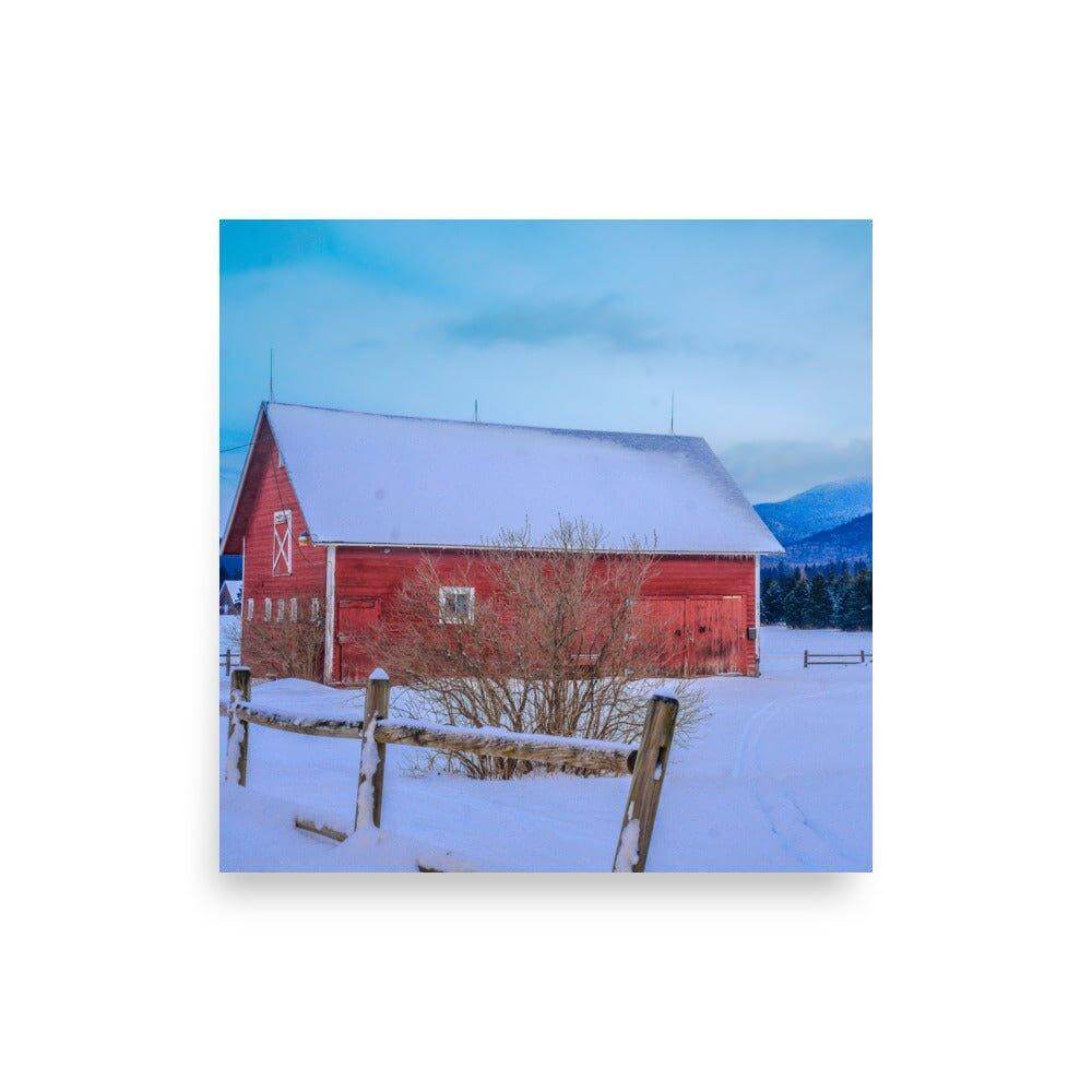 Red barn surrounded by snow with mountains in the background, featured on a matte-finish poster with giclée printing quality.