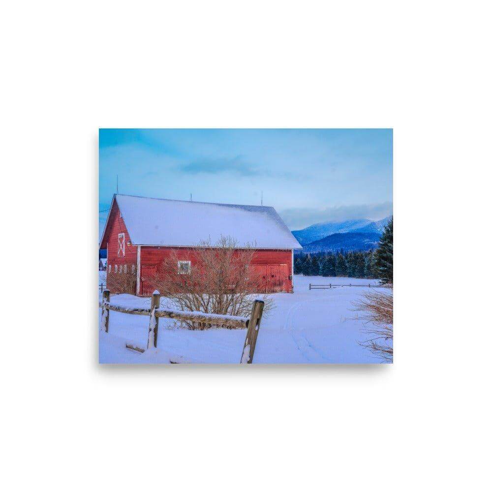 Red mountain barn in a snowy landscape with blue sky and distant forest, featured on matte-finish poster for home decor.